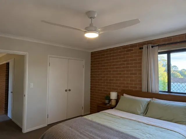 Ceiling fan with light in a bedroom with brick feature wall and window in Birmingham Gardens